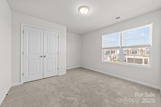 unfurnished bedroom featuring light carpet and a closet