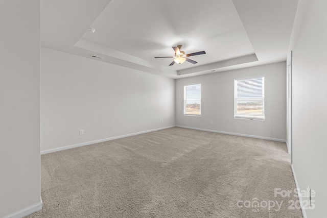 carpeted spare room featuring ceiling fan and a raised ceiling