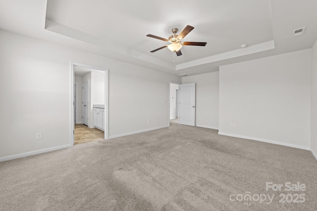 carpeted spare room featuring a tray ceiling and ceiling fan