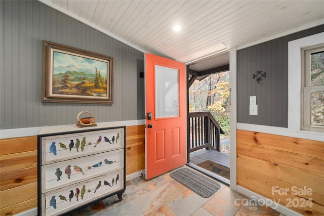 doorway with wood walls, wooden ceiling, and a wealth of natural light