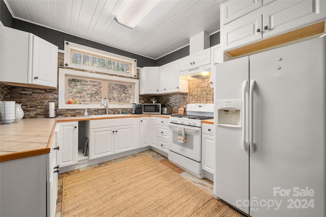 kitchen with decorative backsplash, white appliances, sink, tile countertops, and white cabinetry