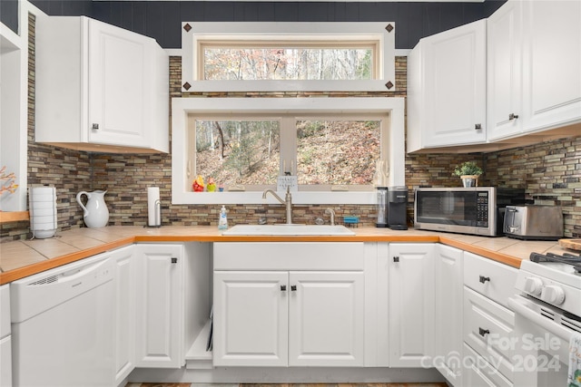 kitchen with tile counters, white cabinetry, white appliances, and sink