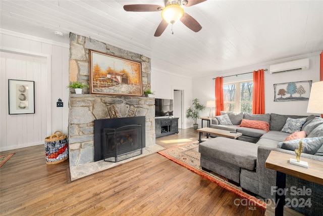 living room with a wall mounted air conditioner, ornamental molding, ceiling fan, wood-type flooring, and a fireplace