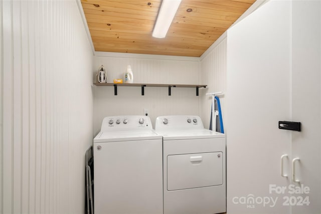 clothes washing area with washer and clothes dryer and wooden ceiling