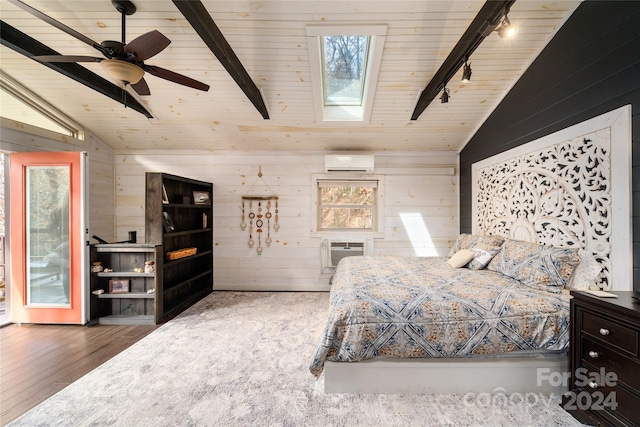 bedroom with track lighting, lofted ceiling with skylight, a wall mounted AC, and ceiling fan