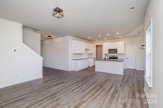 kitchen featuring sink, stainless steel appliances, a center island with sink, white cabinets, and hardwood / wood-style flooring