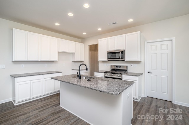 kitchen featuring dark hardwood / wood-style flooring, stainless steel appliances, sink, white cabinets, and an island with sink