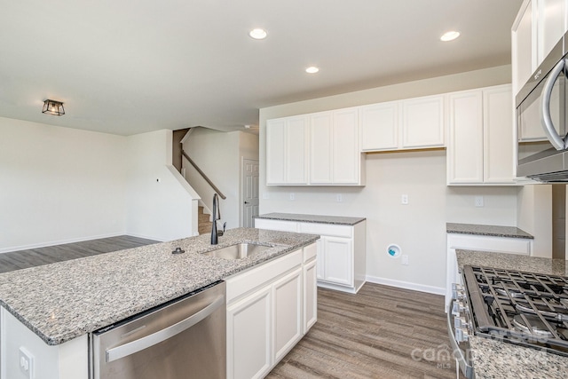 kitchen featuring stainless steel appliances, sink, wood-type flooring, a center island with sink, and white cabinets