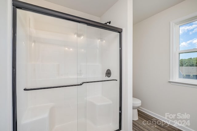 bathroom with wood-type flooring, an enclosed shower, and toilet