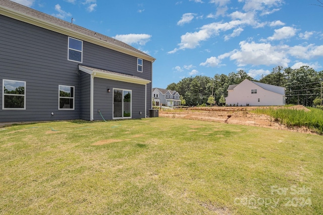 rear view of property with central AC unit and a lawn