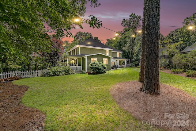 yard at dusk featuring covered porch