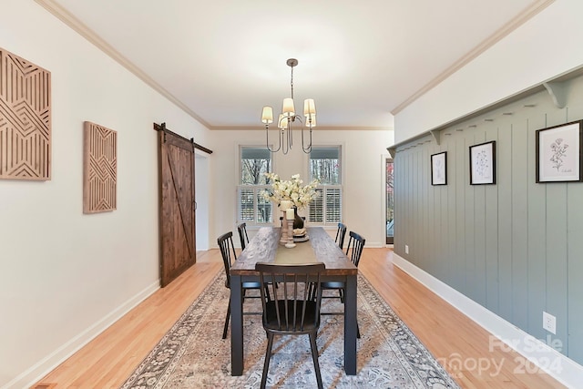 dining area with a chandelier, a barn door, hardwood / wood-style flooring, and crown molding