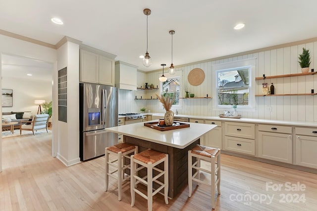 kitchen featuring a center island, decorative light fixtures, a breakfast bar area, appliances with stainless steel finishes, and light wood-type flooring