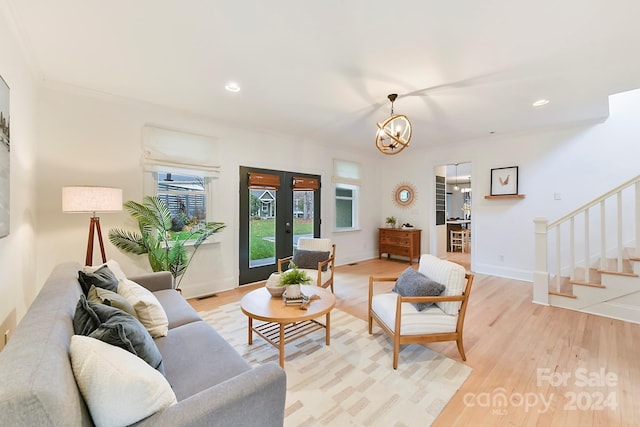 living room with light hardwood / wood-style flooring, french doors, and an inviting chandelier