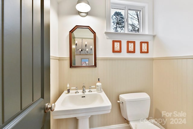 bathroom with toilet, sink, and an inviting chandelier