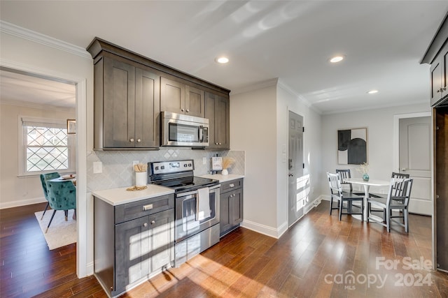 kitchen featuring dark hardwood / wood-style floors, crown molding, and stainless steel appliances