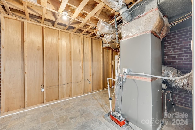 basement with heating unit and brick wall