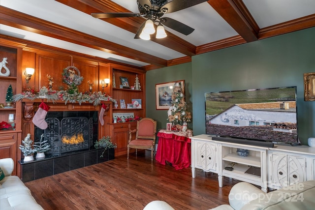 living room with ceiling fan, ornamental molding, beam ceiling, dark hardwood / wood-style flooring, and a tiled fireplace