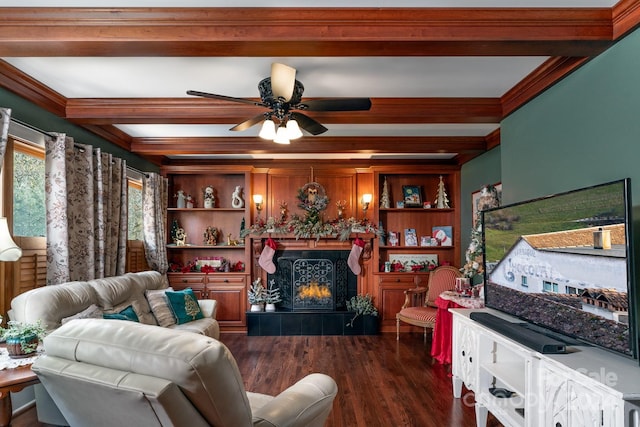 living room featuring dark hardwood / wood-style floors, ceiling fan, built in shelves, ornamental molding, and beamed ceiling