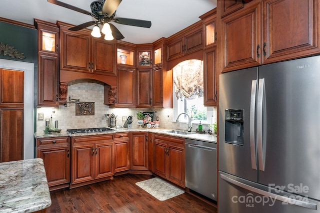 kitchen with ceiling fan, sink, dark wood-type flooring, light stone counters, and appliances with stainless steel finishes