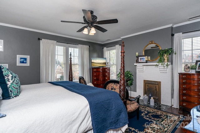 bedroom featuring hardwood / wood-style flooring, a brick fireplace, ceiling fan, and crown molding