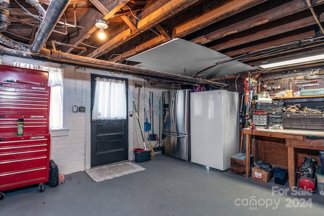 basement with a workshop area, stainless steel fridge with ice dispenser, and refrigerator