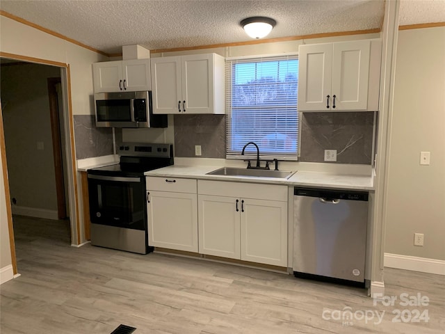 kitchen featuring appliances with stainless steel finishes, tasteful backsplash, sink, light hardwood / wood-style flooring, and white cabinets