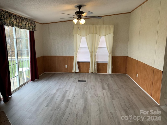 unfurnished room featuring a textured ceiling, light hardwood / wood-style flooring, ceiling fan, and crown molding