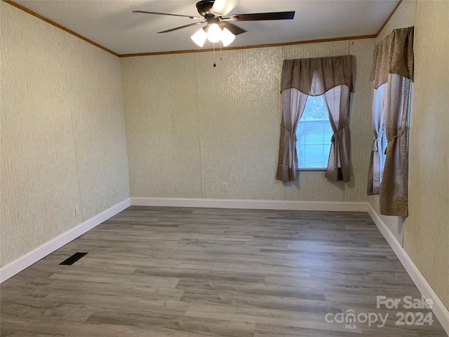 empty room with hardwood / wood-style flooring, ceiling fan, and ornamental molding