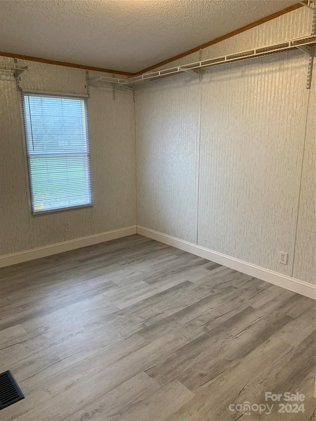 unfurnished room with crown molding, wood-type flooring, and a textured ceiling