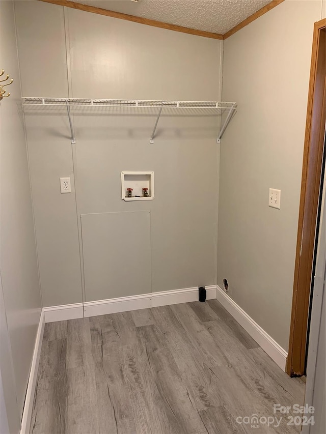 washroom featuring ornamental molding, washer hookup, a textured ceiling, and hardwood / wood-style flooring