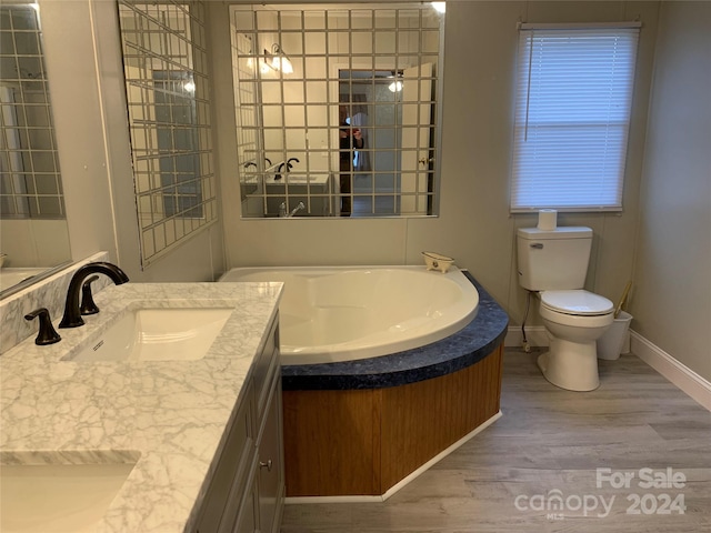 bathroom featuring hardwood / wood-style flooring, vanity, toilet, and a bath