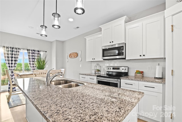 kitchen featuring white cabinets, sink, hanging light fixtures, an island with sink, and stainless steel appliances