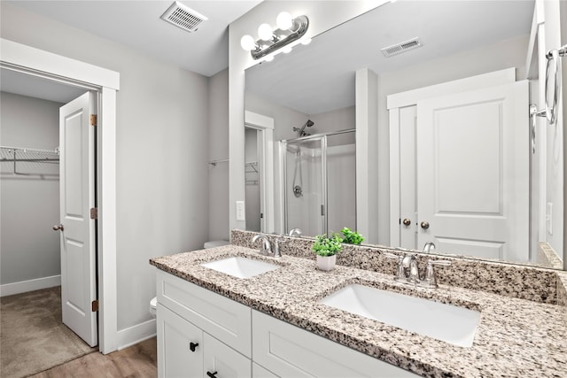 bathroom with wood-type flooring, vanity, and a shower with shower door