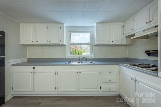 kitchen with black refrigerator, sink, hardwood / wood-style flooring, white cabinetry, and white electric stovetop