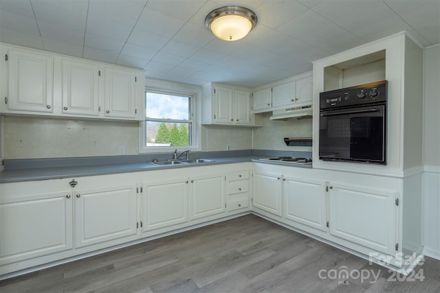 kitchen featuring white cabinetry, black oven, light hardwood / wood-style floors, and sink