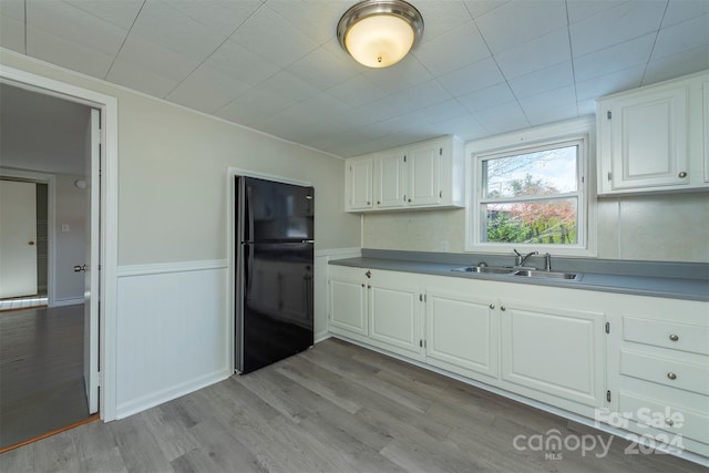 kitchen with black refrigerator, light wood-type flooring, white cabinetry, and sink