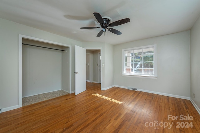 unfurnished bedroom featuring ceiling fan, wood-type flooring, and a closet