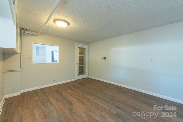 unfurnished room featuring a textured ceiling and dark hardwood / wood-style floors