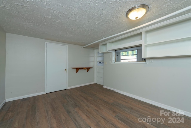 basement featuring a textured ceiling and dark hardwood / wood-style flooring