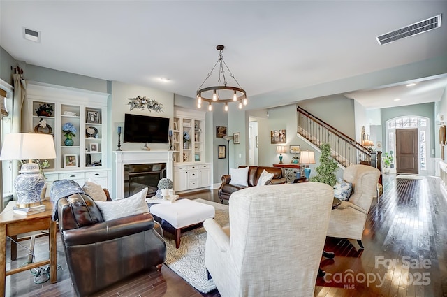 living room with dark hardwood / wood-style floors, a chandelier, and built in shelves