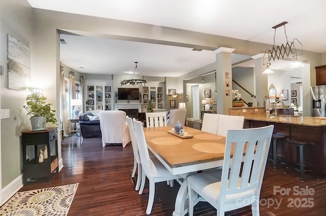 dining room with a multi sided fireplace and dark hardwood / wood-style floors