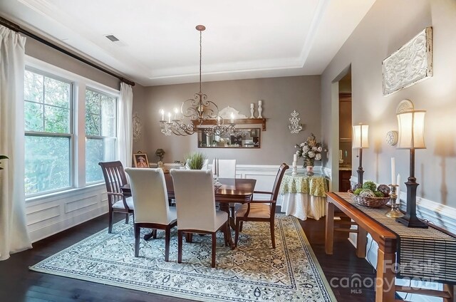 dining room with a tray ceiling, dark hardwood / wood-style flooring, a chandelier, and a wealth of natural light