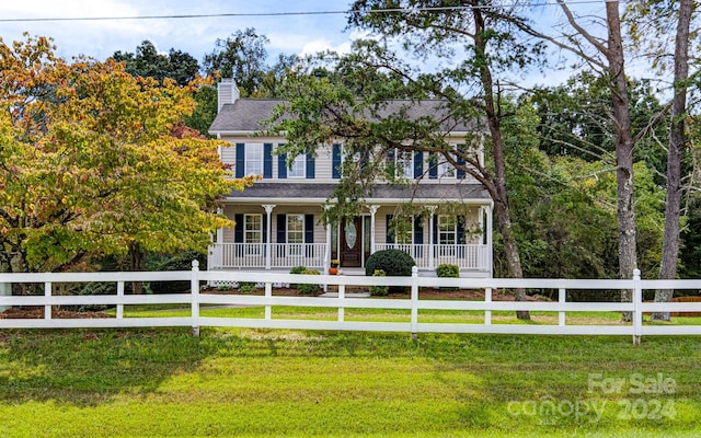 colonial home featuring a front lawn and covered porch