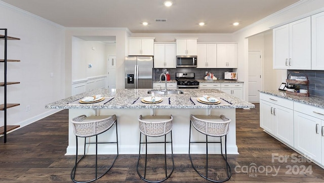 kitchen featuring sink, stainless steel appliances, white cabinetry, and an island with sink