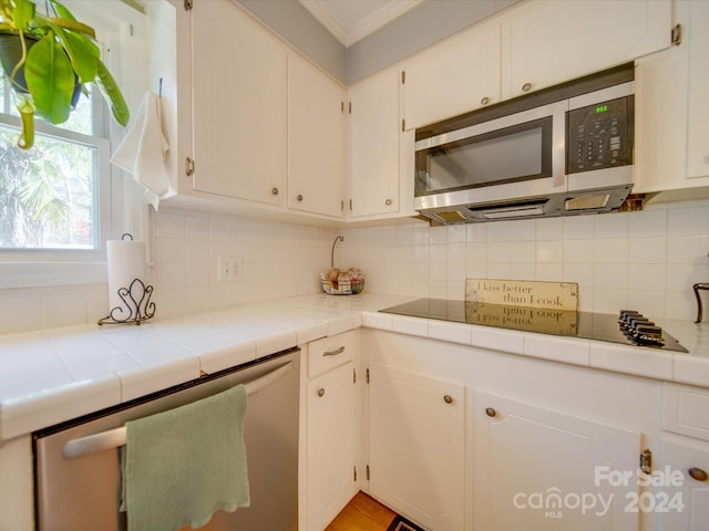 kitchen featuring tasteful backsplash, tile countertops, white cabinetry, and appliances with stainless steel finishes