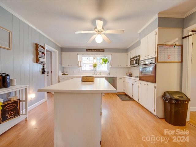 kitchen featuring a center island, white cabinetry, stainless steel appliances, and ornamental molding