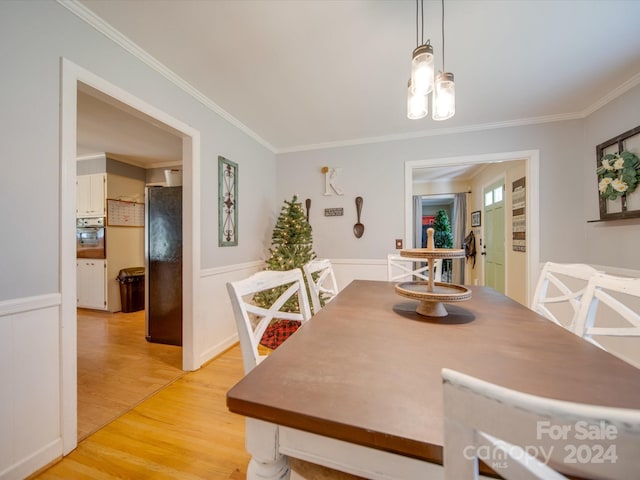 dining space with a notable chandelier, ornamental molding, and light hardwood / wood-style flooring