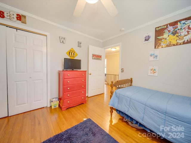 bedroom featuring hardwood / wood-style flooring, ceiling fan, crown molding, and a closet