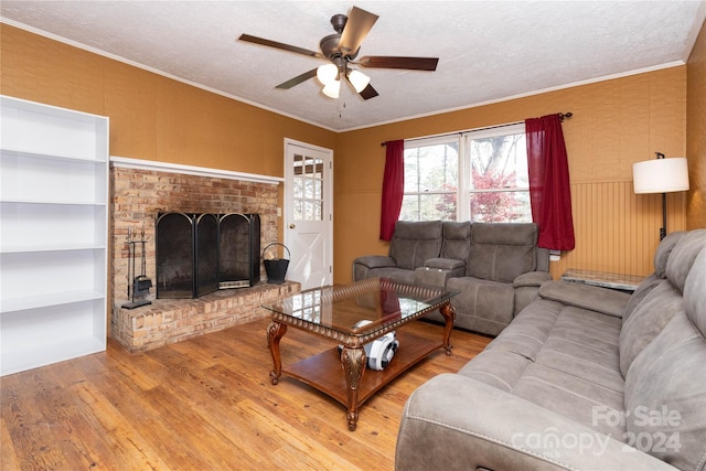 living room featuring crown molding, a brick fireplace, hardwood / wood-style flooring, ceiling fan, and a textured ceiling